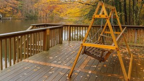 A wooden deck with a wooden swing set and a bench. - Eagle Lake Cabin Coalmont (Coalmont)