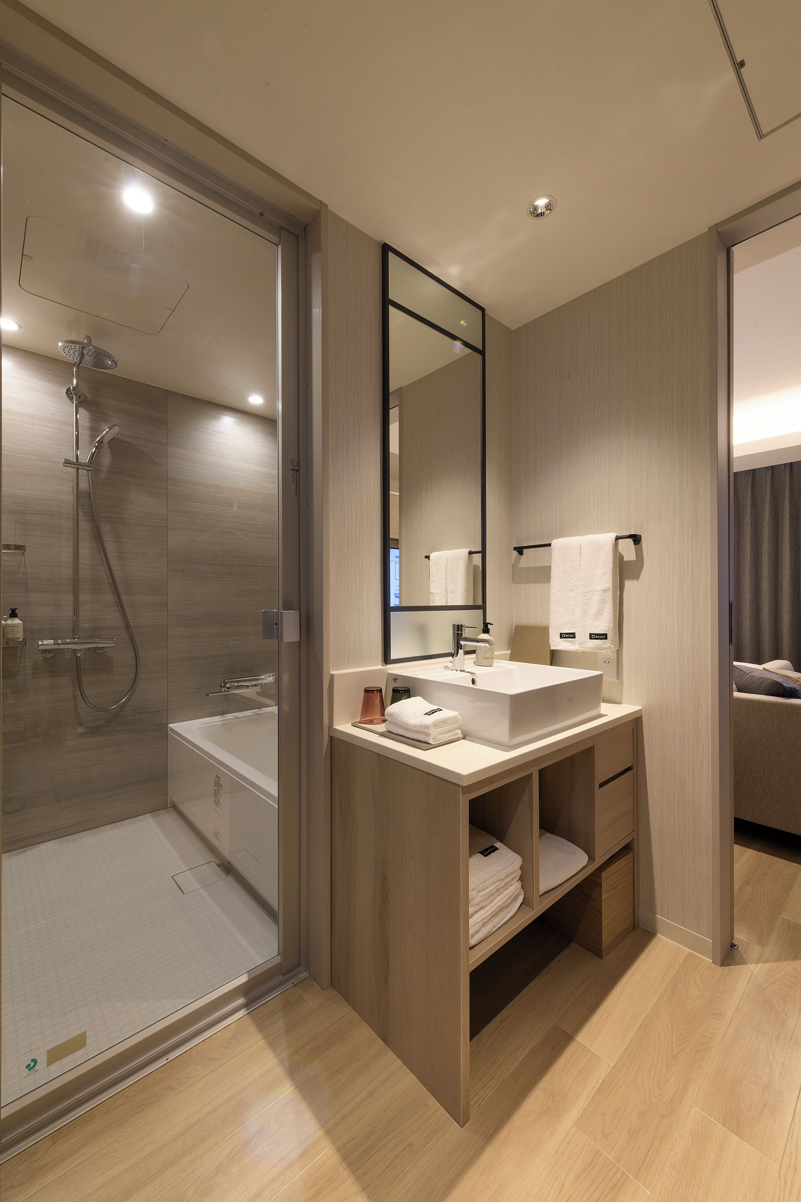 Un baño moderno con ducha envuelta en vidrio, una bañera independiente y un tocador con espejo.