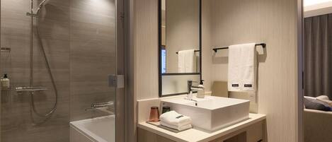 Un baño moderno con ducha envuelta en vidrio, una bañera independiente y un tocador con espejo.