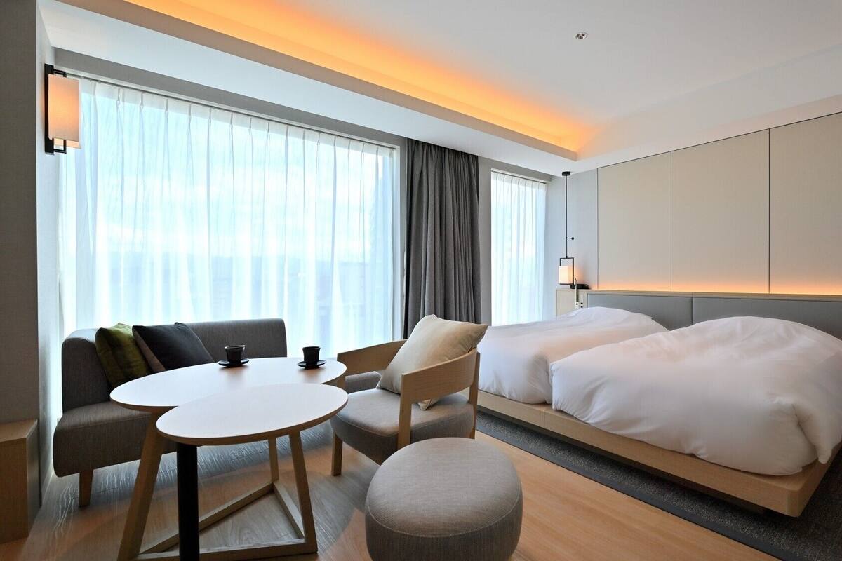 Une chambre d’hôtel comprenant un lit, deux tables de chevet, un canapé, une table ronde et une chaise.
