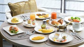 Uma mesa de café da manhã com diversos pratos, utensílios e uma bebida.