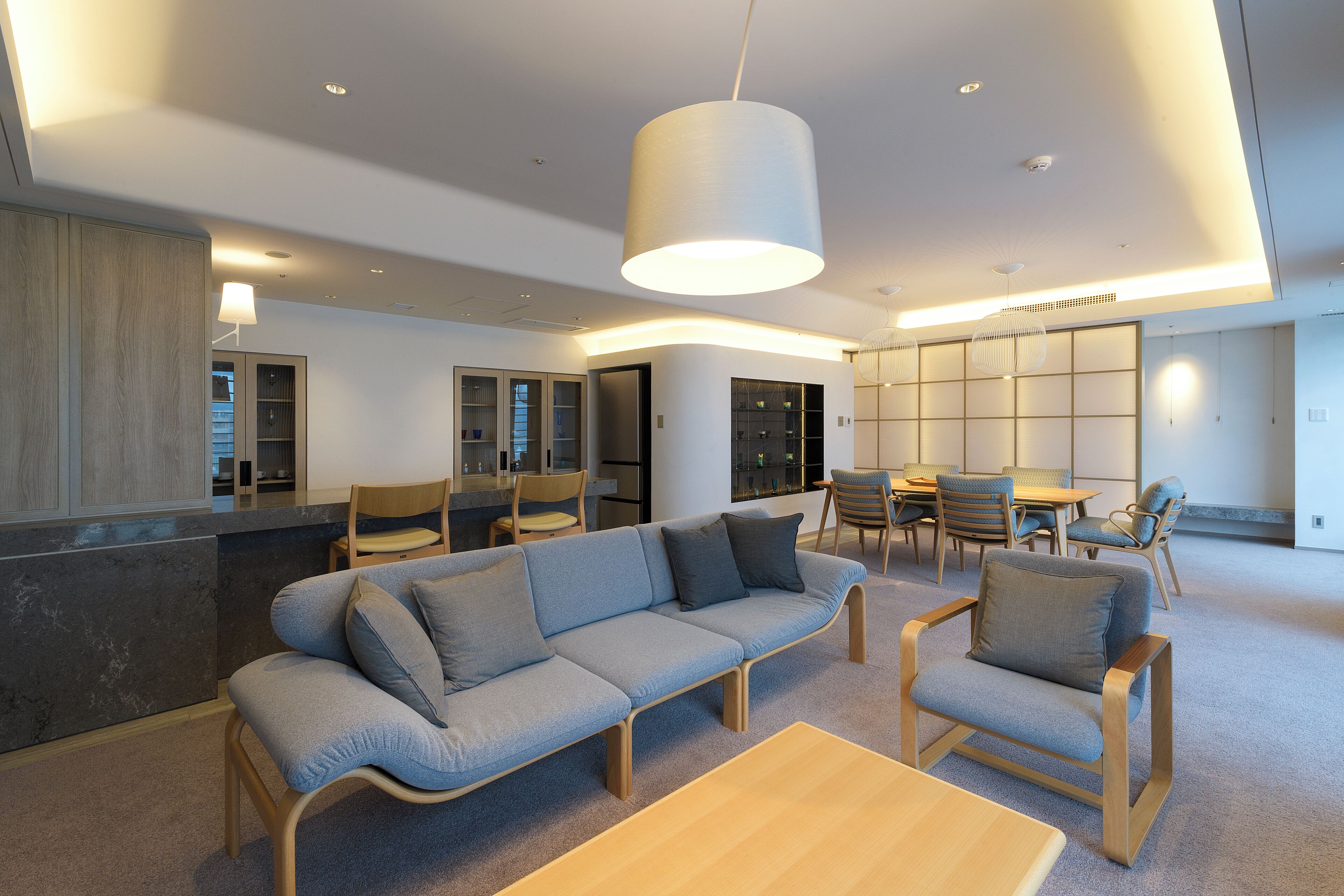 Un intérieur moderne comprenant un canapé, des fauteuils, un coin repas et une cuisine.
