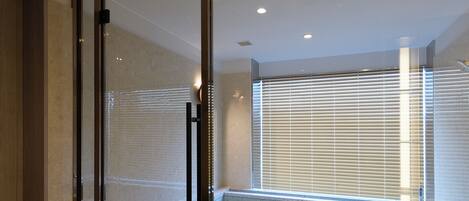 A modern bathroom with a glass partition, a bathtub, and a shower area.