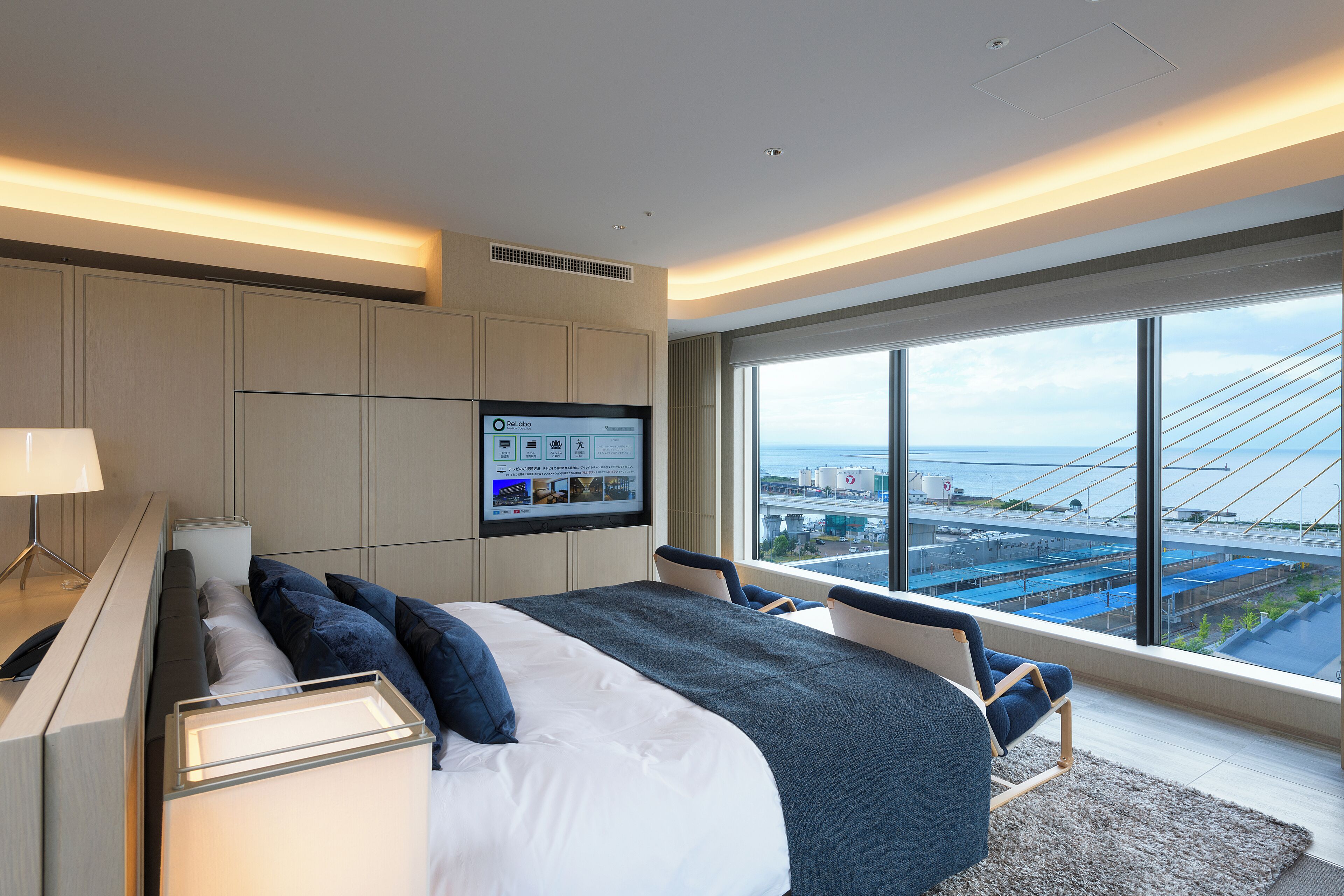 A modern hotel room with a large bed, a desk, and a TV displaying a room service menu.