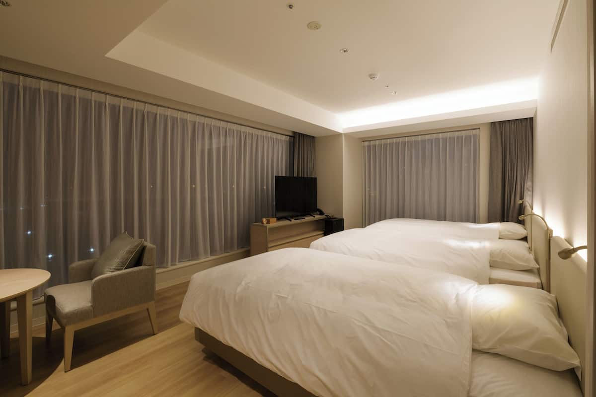 Une chambre d’hôtel avec deux lits, un bureau et une télévision.