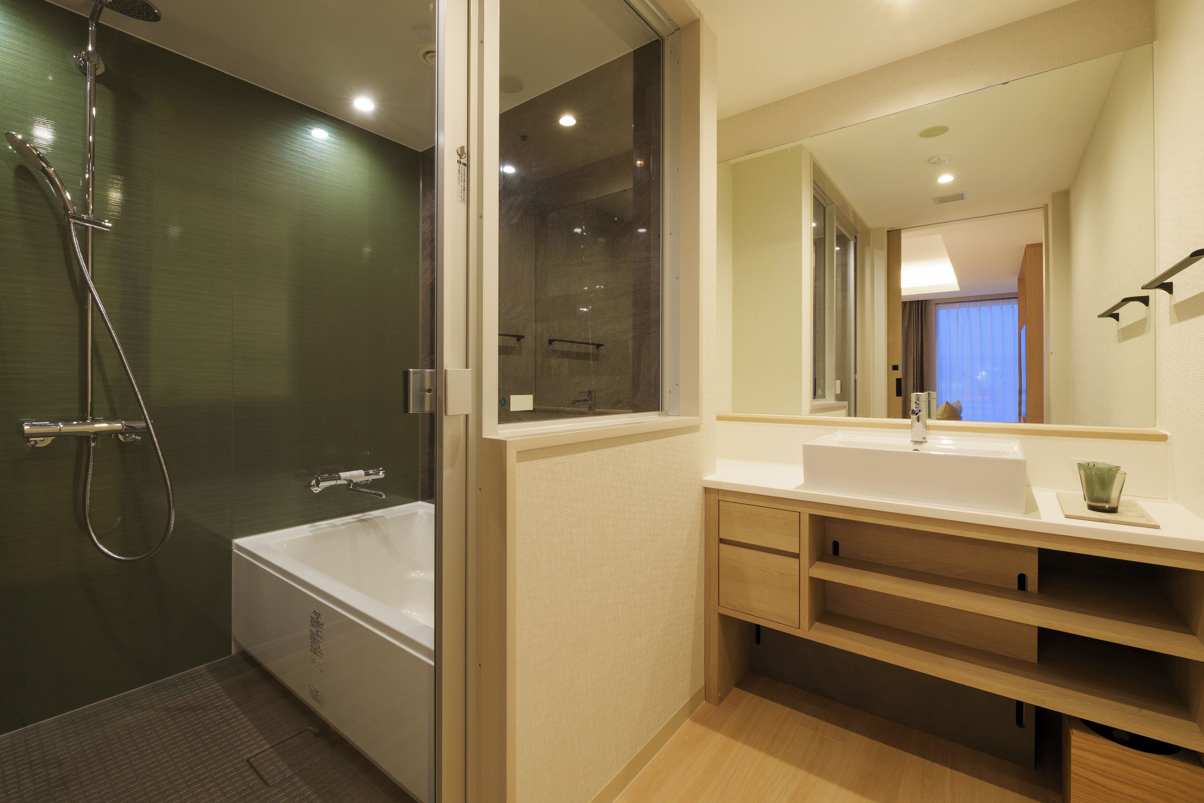A modern bathroom with a glass-enclosed shower, a white bathtub, and a large mirror above a white sink with wooden cabinets.