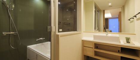 A modern bathroom with a glass-enclosed shower, a white bathtub, and a large mirror above a white sink with wooden cabinets.