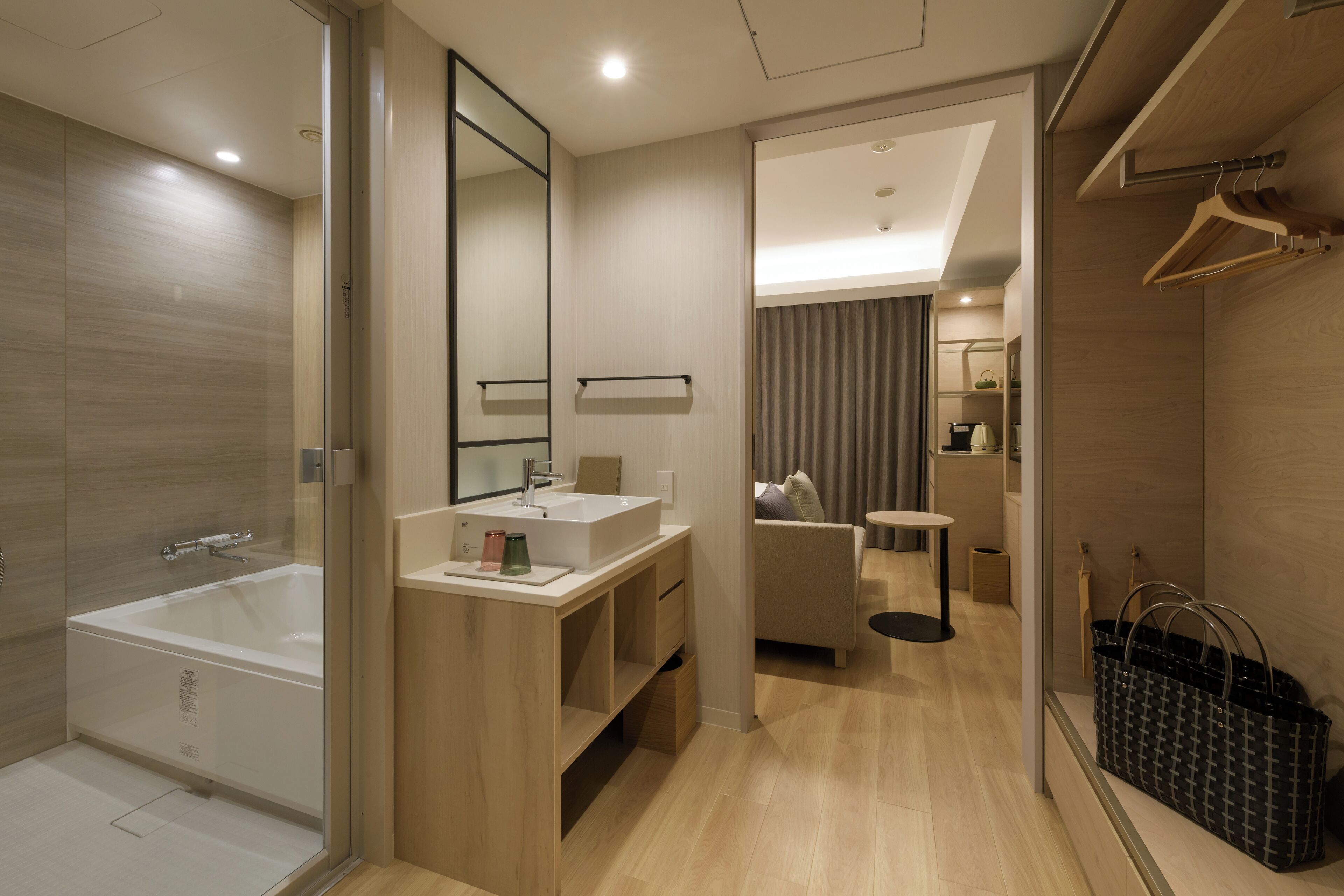 Un bagno moderno con vasca, lavabo e specchio. È presente una zona relax con divano e tavolino.