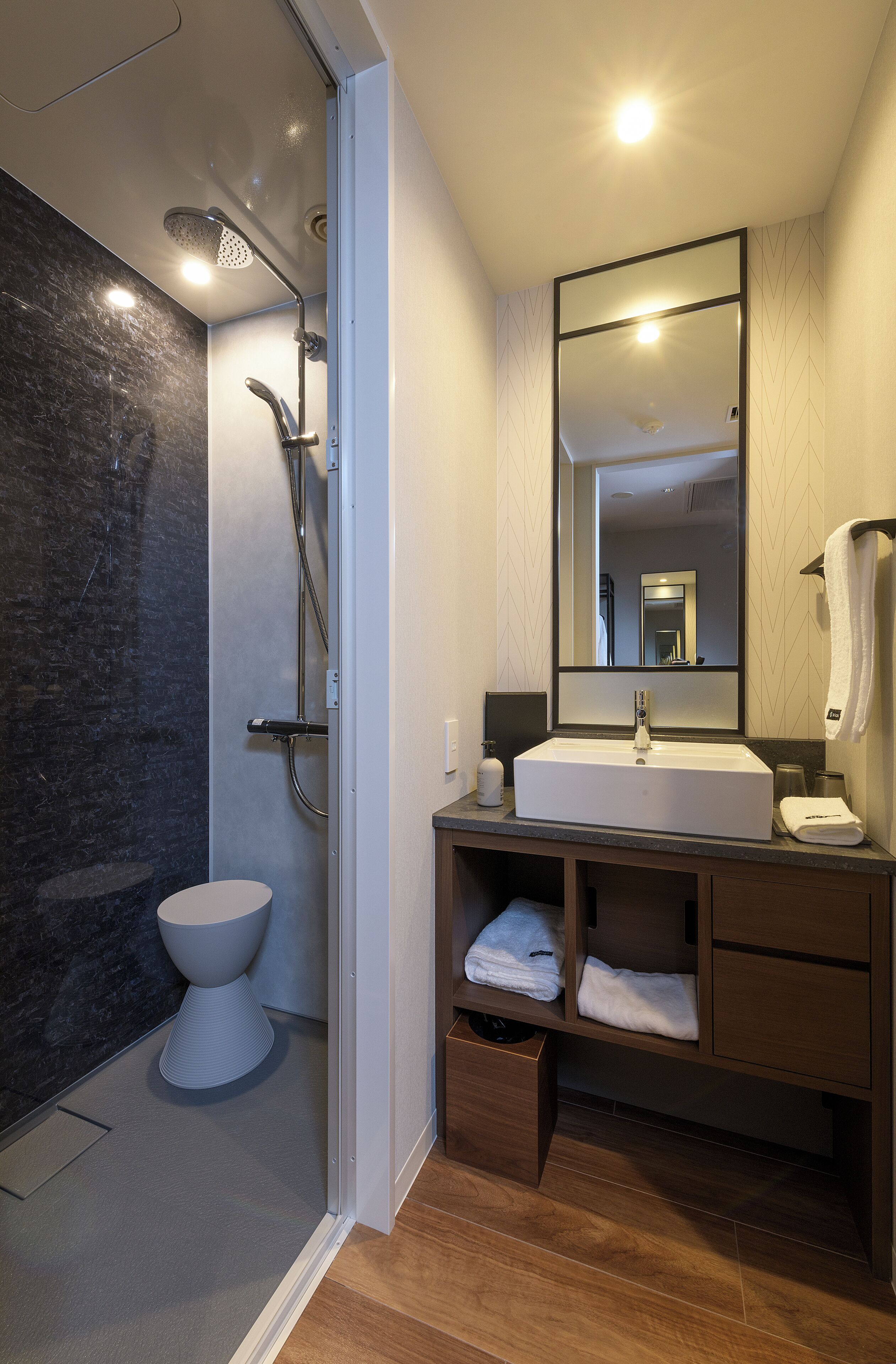 A modern bathroom with a shower, toilet, and sink.
