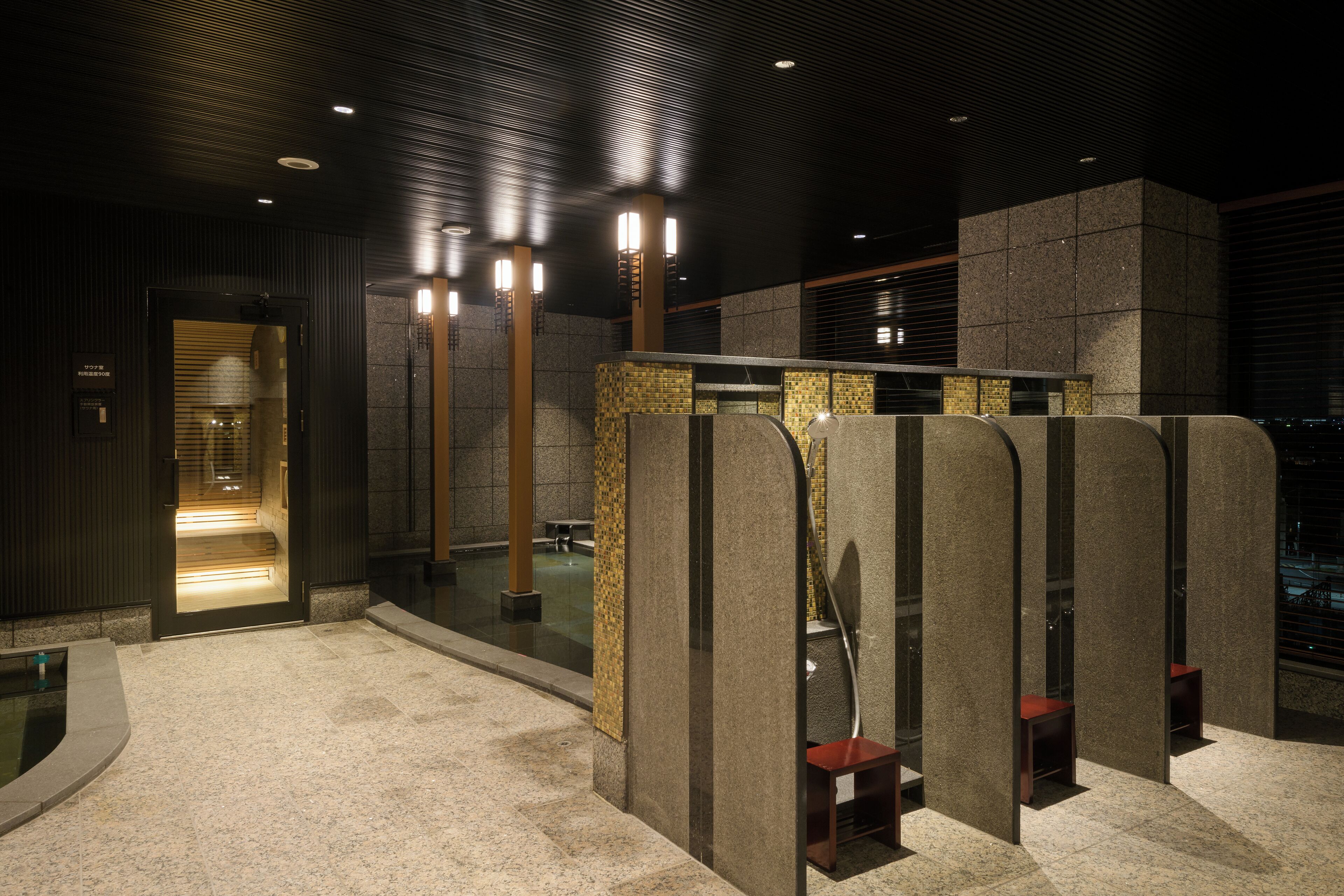 Une salle de bain moderne dotée d’une grande baignoire, d’une douche à l’italienne et d’un espace détente avec des bancs.