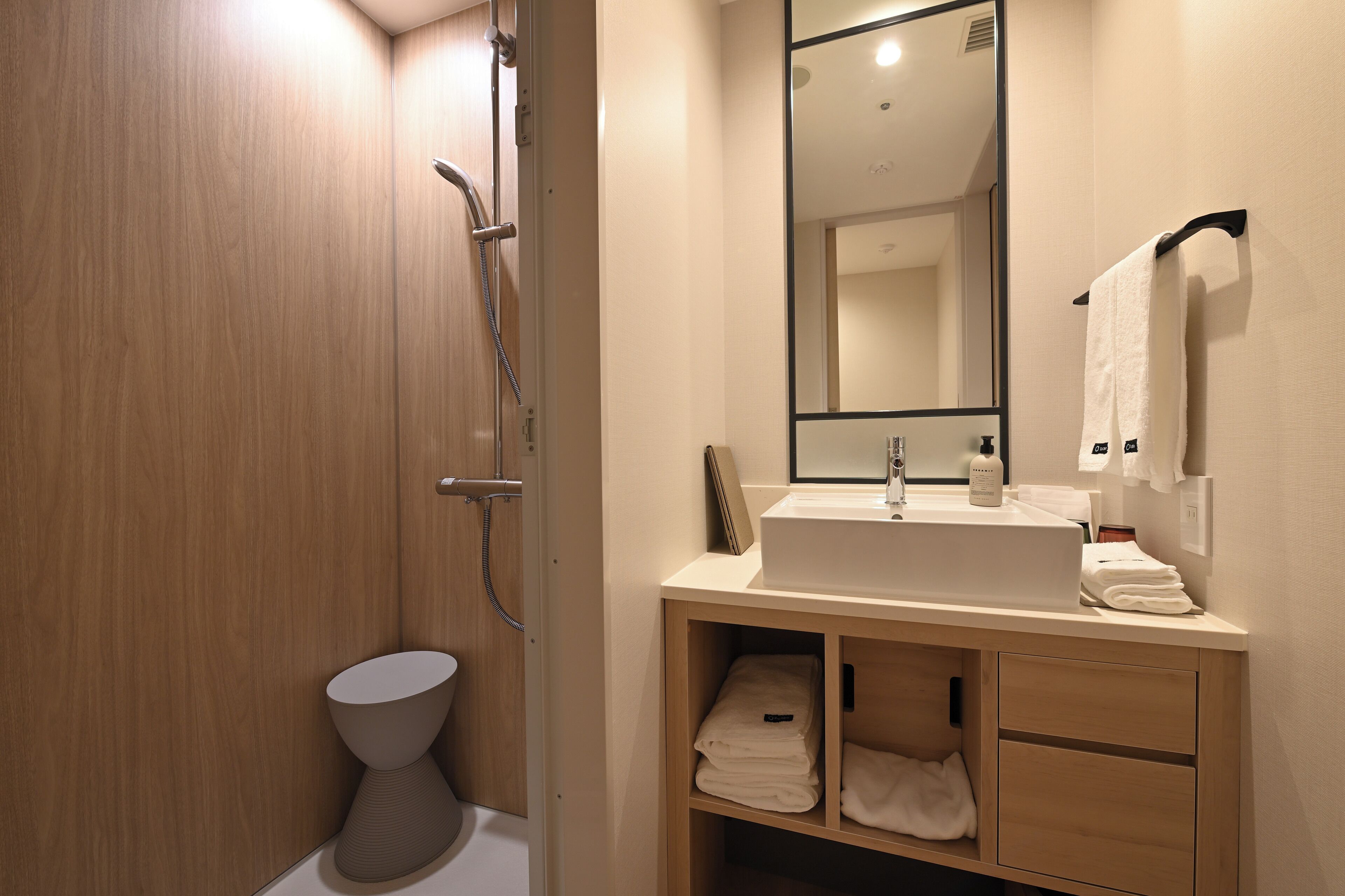 A modern bathroom with a wooden vanity, a large mirror, and a shower.