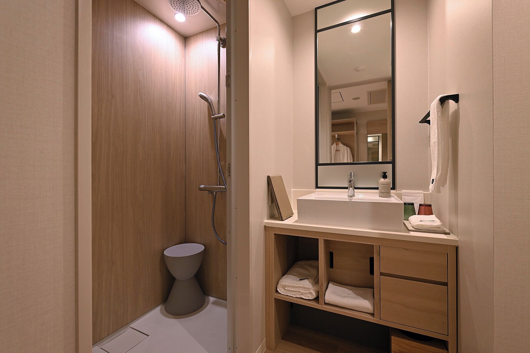 A modern bathroom with a shower, a sink, a mirror, and a toilet.