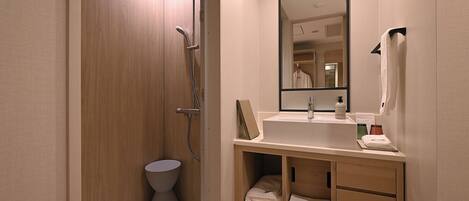 A modern bathroom with a shower, a sink, a mirror, and a toilet.