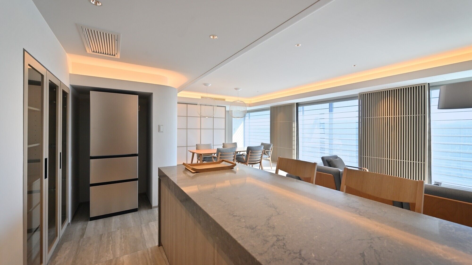 A modern kitchen with a marble countertop, built-in appliances, and a seating area with chairs and a table.