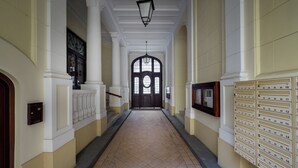 Un couloir avec un sol carrelé, des boîtes aux lettres et une porte au fond.