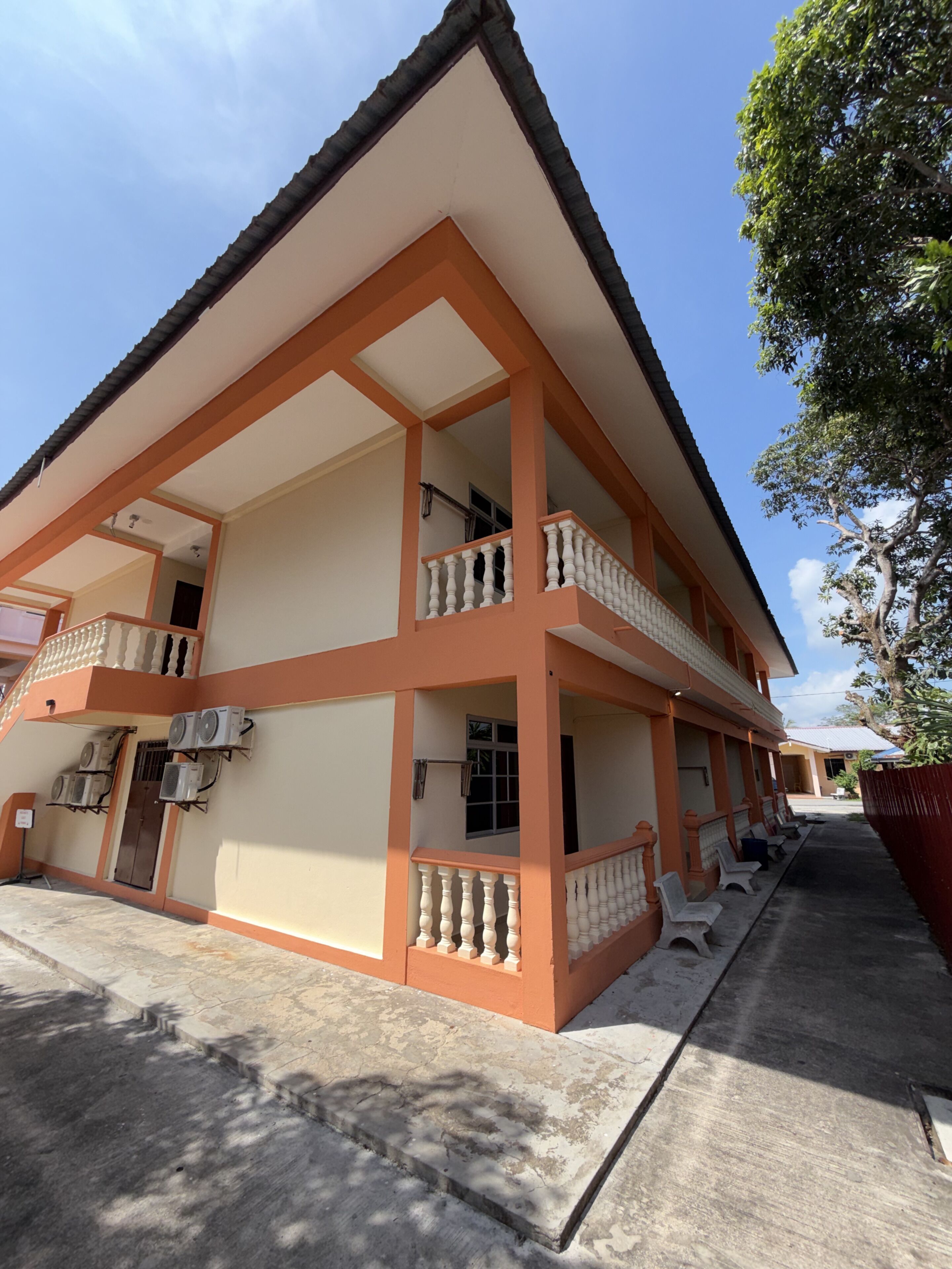 Um edifício com vários andares, varandas, aparelhos de ar condicionado e um chão de concreto.