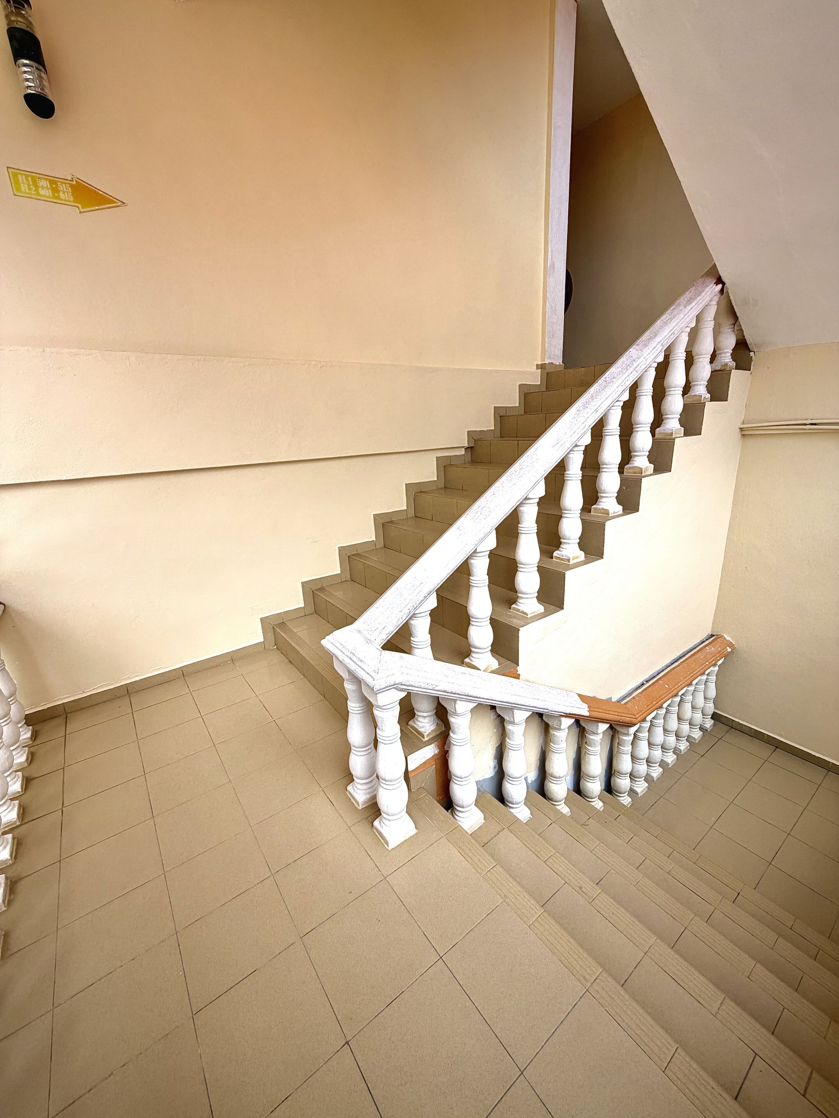 A staircase with white balusters and a wooden handrail, leading to an upper floor.