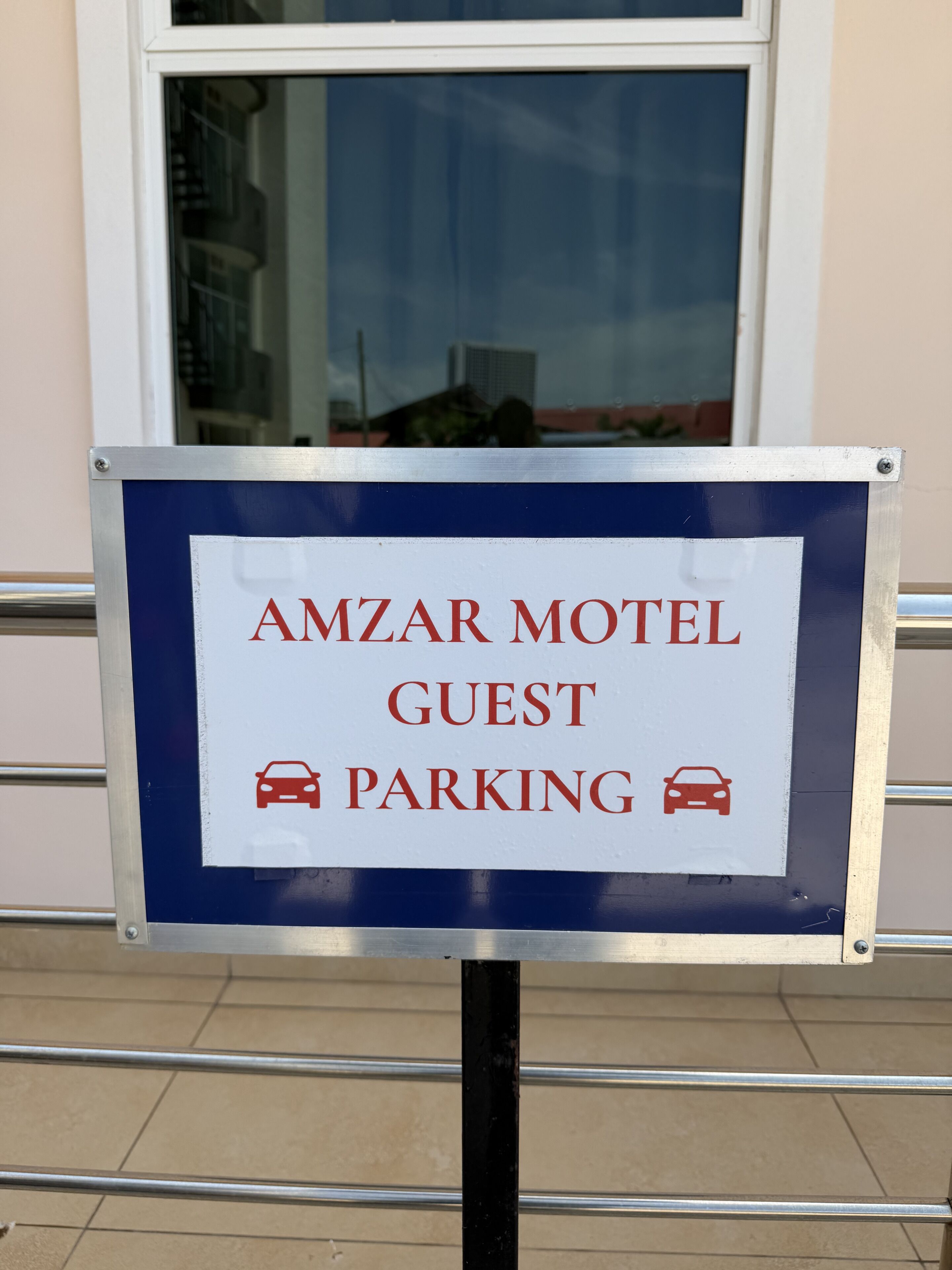 Amzar Motelin asiakaspysäköinnin opastekyltti, jossa on auton kuva.