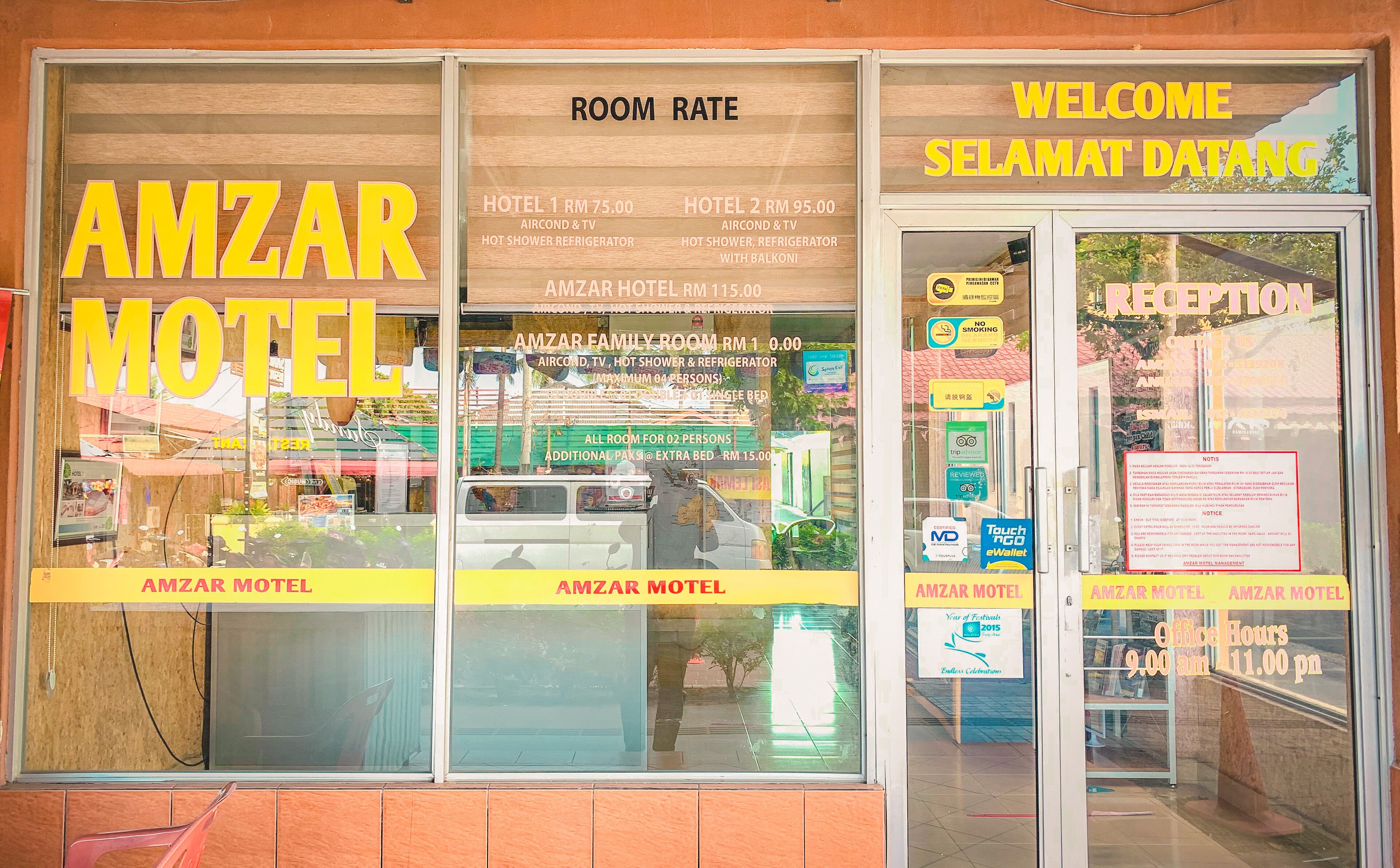 The AMZAR MOTEL with a clear view of the room rate sign, welcoming sign, and a glimpse of the interior.