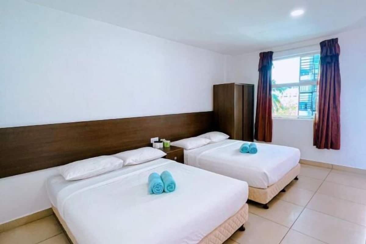 A hotel room with two beds, a wooden headboard, a wardrobe, and a window with curtains.