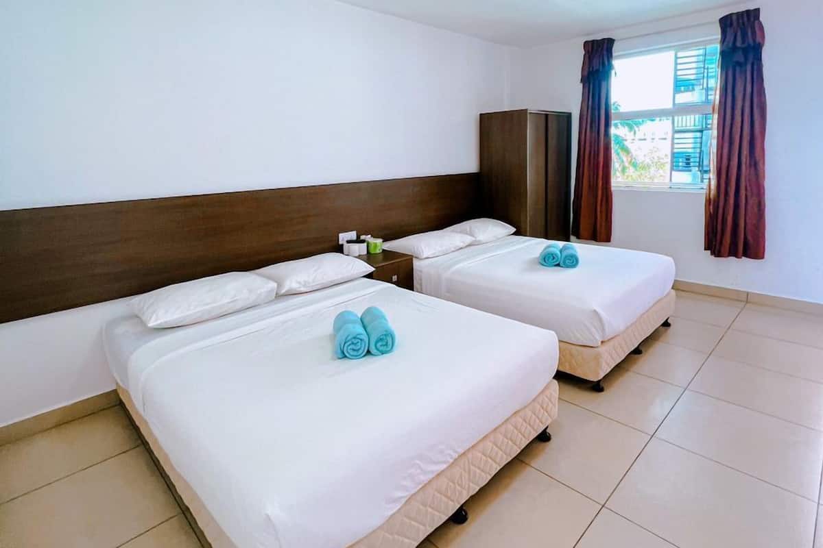 A hotel room with two beds, a wooden headboard, a nightstand, and a window with curtains.