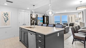 A modern kitchen with a central island, dark cabinetry, and pendant lighting. - Blu 300 ~ Stunning 4BR w/ Gulf Views ~ Free Beach Service (Fort Walton Beach)