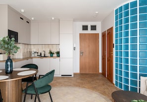 A modern kitchen with white cabinets, a wooden door, and a blue tiled wall.