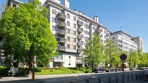A multi-story residential building with balconies, a clear sky, and parked cars along the street. - Saska Kępa Cosy Studio (Warszawa)
