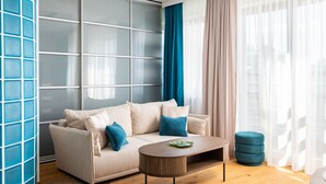 A modern living room with a beige sofa, blue cushions, a wooden coffee table, and a blue ottoman. - Saska Kępa Cosy Studio (Warszawa)