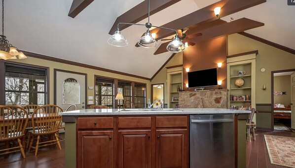 A spacious kitchen with a large island, wooden cabinets, and a stone backsplash.