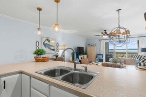 A kitchen with a double sink, pendant lights, and a view of the ocean.