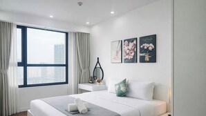 A modern hotel room with a large bed, a desk, and a view of the city.