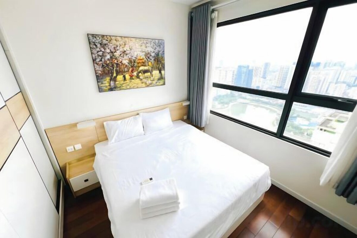 Habitación de hotel con cama, un cuadro en la pared y un ventanal con vistas a la ciudad.