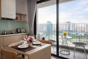 A modern kitchen with a dining area, a washing machine, and a balcony with a city view.
