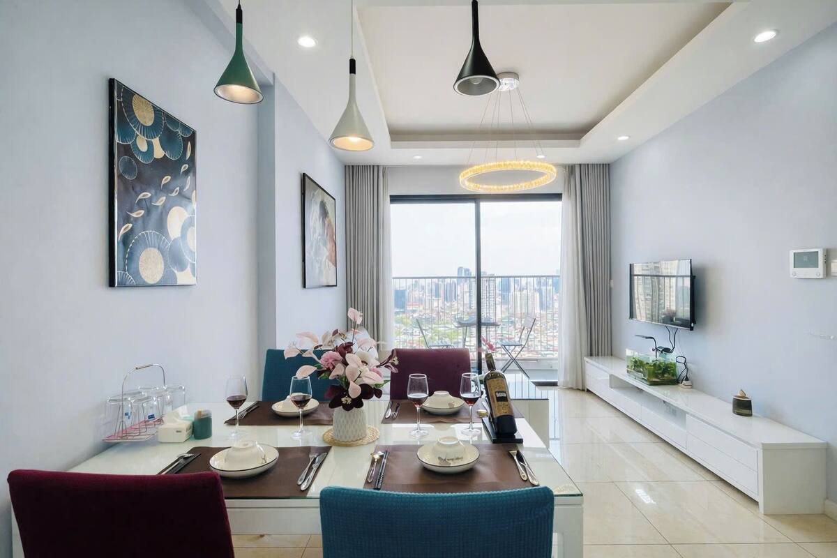 A modern dining area with a city view, a TV, and a balcony with a plant.