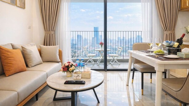 A modern living room with a sofa, coffee table, and dining area with a view of the cityscape.