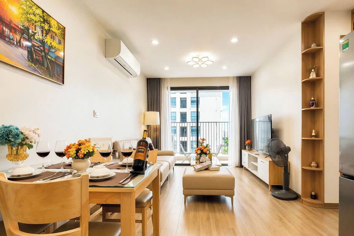 A modern living room with a dining area, a sofa, a TV, and a balcony with a view.
