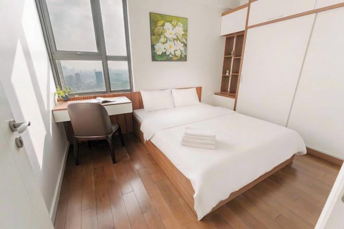 A hotel room with a bed, a desk, a chair, and a large window.