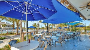 Un espace extérieur avec une piscine, des parasols bleus, des chaises longues et des tables.