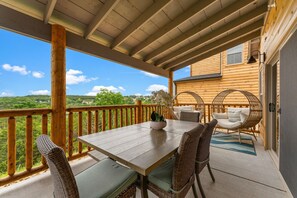 Una terraza de madera con mesa y sillas, con vistas a un paisaje pintoresco.