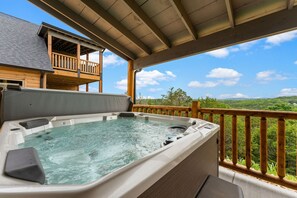 Un jacuzzi en una terraza de madera con vistas a un paisaje boscoso.
