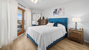 A bedroom with a large bed, a nightstand with a lamp, a mirror, and a painting on the wall. - La Mirage Condo 203 Beachfront Resort Condominiums with Private Boardwalk (Port Aransas)