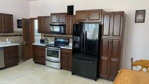 Una cocina moderna con armarios de madera, electrodomésticos de acero inoxidable y suelo de baldosas.