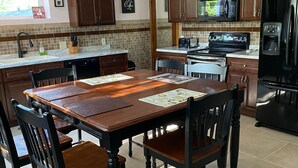 Una cocina amplia con una isla grande, armarios de madera, un refrigerador negro y un microondas.