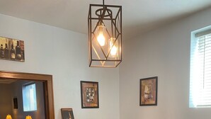 Una zona de bar con taburetes de madera, una barra y una lámpara colgante.