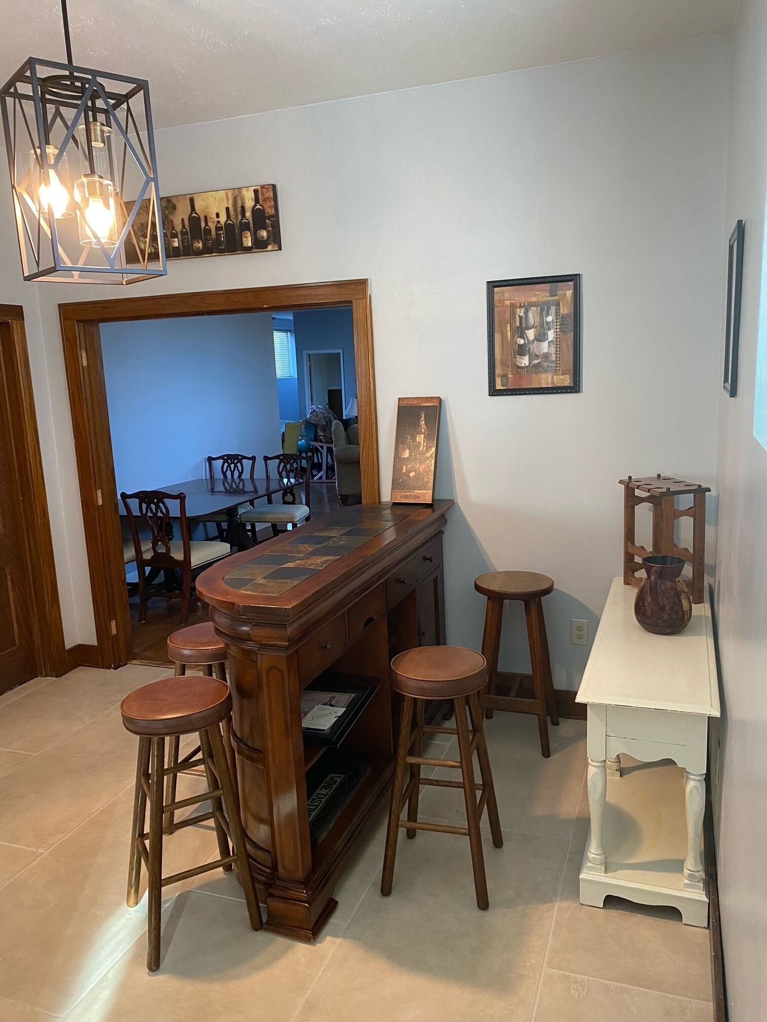 Een bar met krukken, een houten toonbank en een hangende lamp.