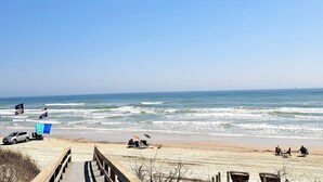 A beach with a wooden boardwalk leading to the shore, where people are sitting under umbrellas and on beach chairs. - La Mirage Condo 316LK Beachfront Resort Condominiums with Private Boardwalk (Port Aransas)