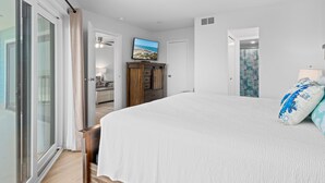 Ein Schlafzimmer mit einem großen Bett, einem Fernseher an der Wand und Meerblick durch das Fenster.