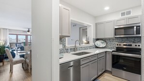 A modern kitchen with stainless steel appliances, a dishwasher, and a dining area with a table and chairs.
