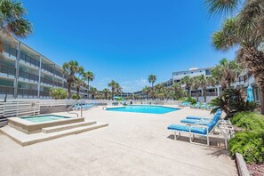 A hotel pool area with a clear blue pool, lounge chairs, and palm trees. - La Mirage Condo 303LK Beachfront Resort Condominiums with Private Boardwalk (Port Aransas)